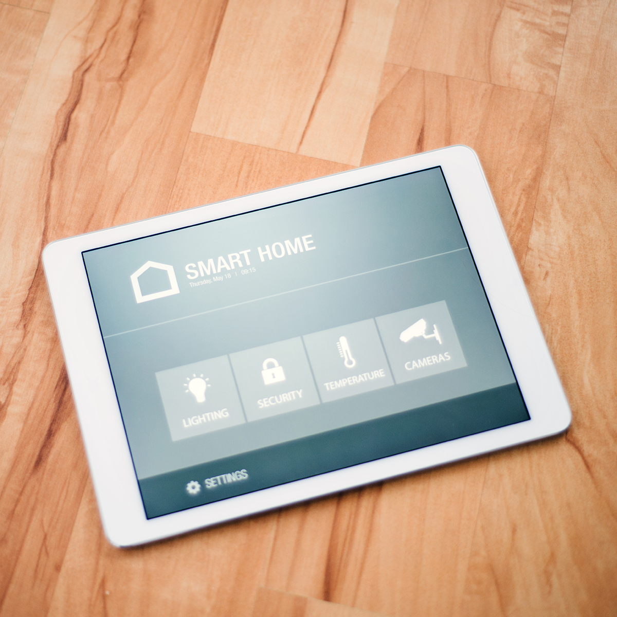 FGV Impianti Biella S.R.L. Domotica Tablet domotico per gestione impianti di casa e ufficio.
Tablet con interfaccia “Smart Home” appoggiato su piano in legno chiaro, che mostra funzioni per la gestione di luci, sicurezza, riscaldamento e impianti elettrici. Lo schermo retroilluminato è ben leggibile e inserito in un ambiente moderno.