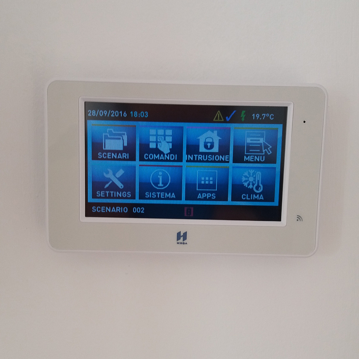 Fgv Impianti Biella Srl Antintrusione Display touchscreen da parete con interfaccia domotica per antintrusione
Display touchscreen Antintrusione con schermo a colori installato a parete con interfaccia grafica a icone. Sono visibili diverse funzioni per la gestione di climatizzazione, luci, sicurezza e altri dispositivi di domotica. La cornice del display è bianca.