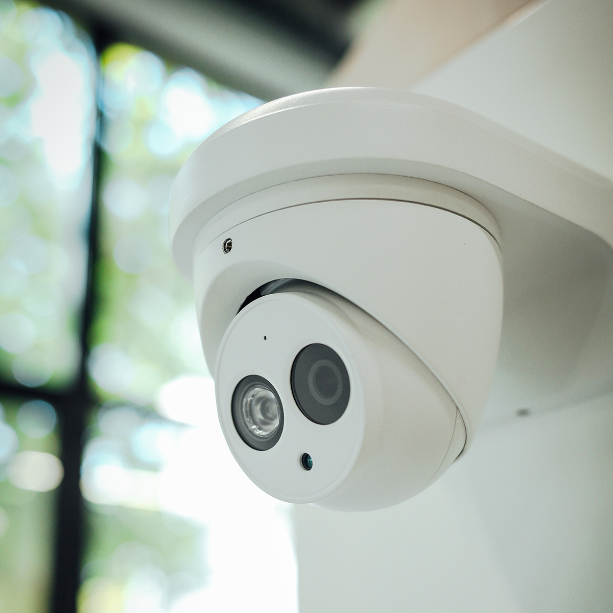 FGV Impianti Biella S.R.L. Videosorveglianza Telecamera di videosorveglianza bianca orientata verso il basso
Telecamera di sicurezza di colore bianco fissata a una staffa e orientata verso il basso. L’obiettivo è rivolto frontalmente e la scocca ha forma tondeggiante. L’immagine è un primo piano mentre lo sofndo sfocato mostra una grossa finestra che affaccia su una zona verdeggiante